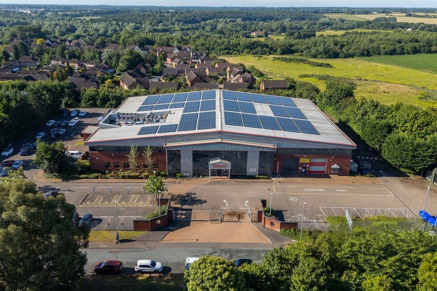 Overhead perspective of a sizable industrial facility with solar panels on the roof, highlighting renewable energy solutions.