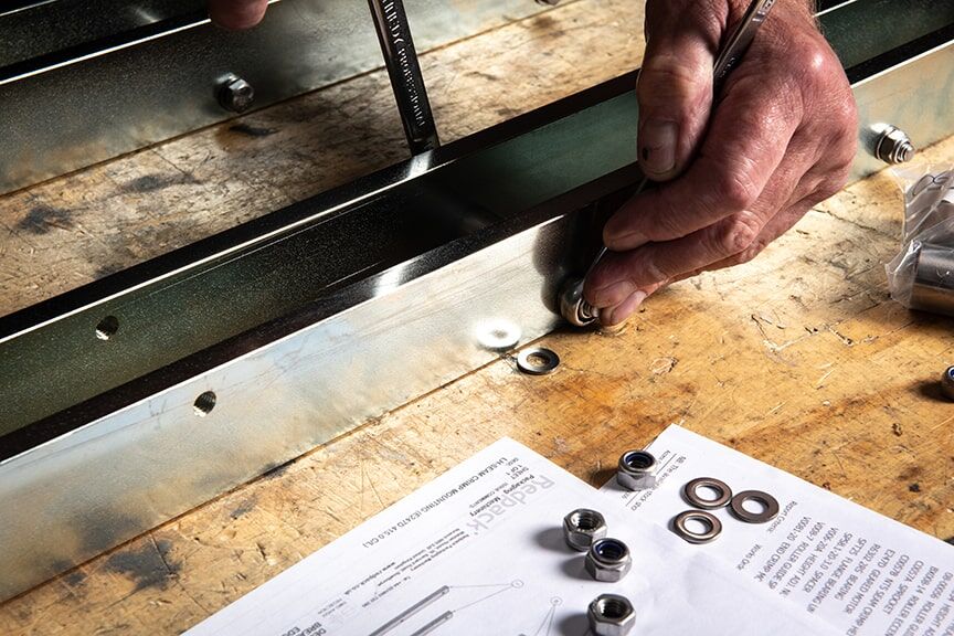 A man carefully assembles a metal frame, using screws to secure the components together.