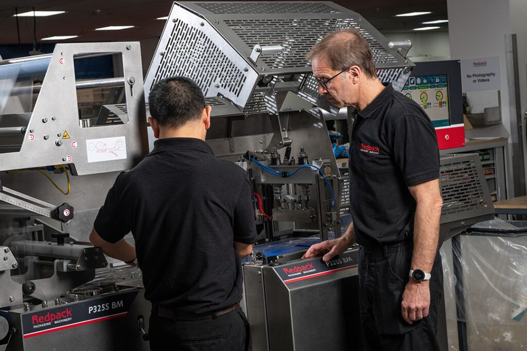 Two factory workers operating a machine, demonstrating teamwork and concentration in an industrial environment.