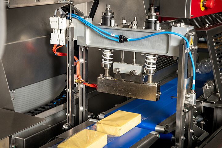 A machine processes milk into cheese in a factory setting, showcasing industrial cheese production.