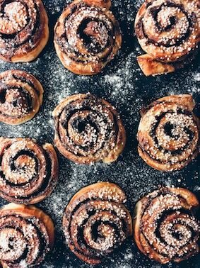 Freshly baked chocolate cinnamon buns arranged on a baking sheet, showcasing their rich, gooey texture and golden-brown color.