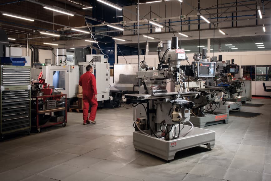 A man stands in a factory surrounded by various machines, showcasing an industrial work environment.