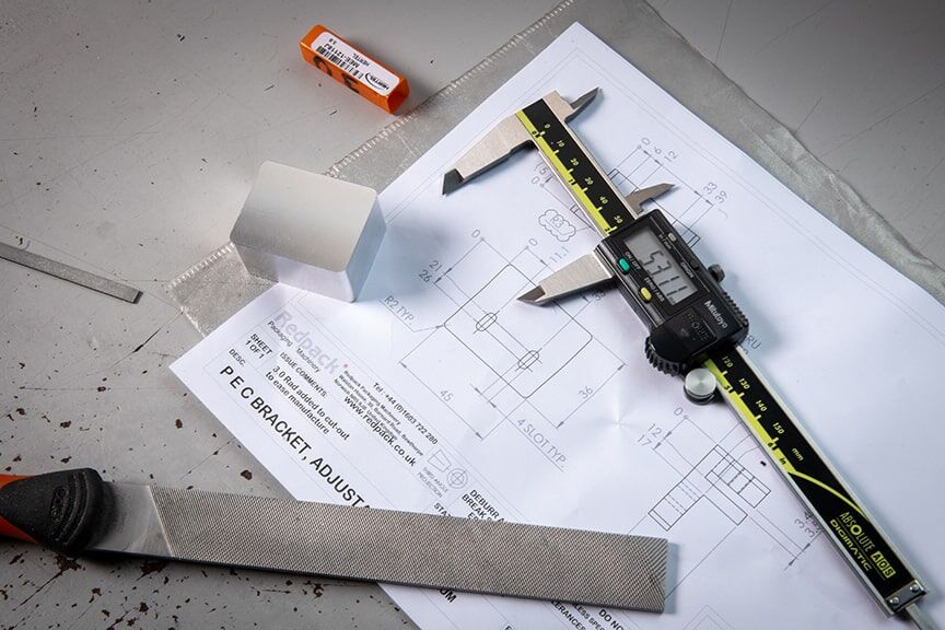 An image featuring calipers, a ruler, and a piece of paper, essential tools for accurate measurement and design work.