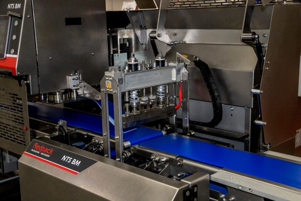 A factory machine is actively creating a blue tray, illustrating the manufacturing workflow.